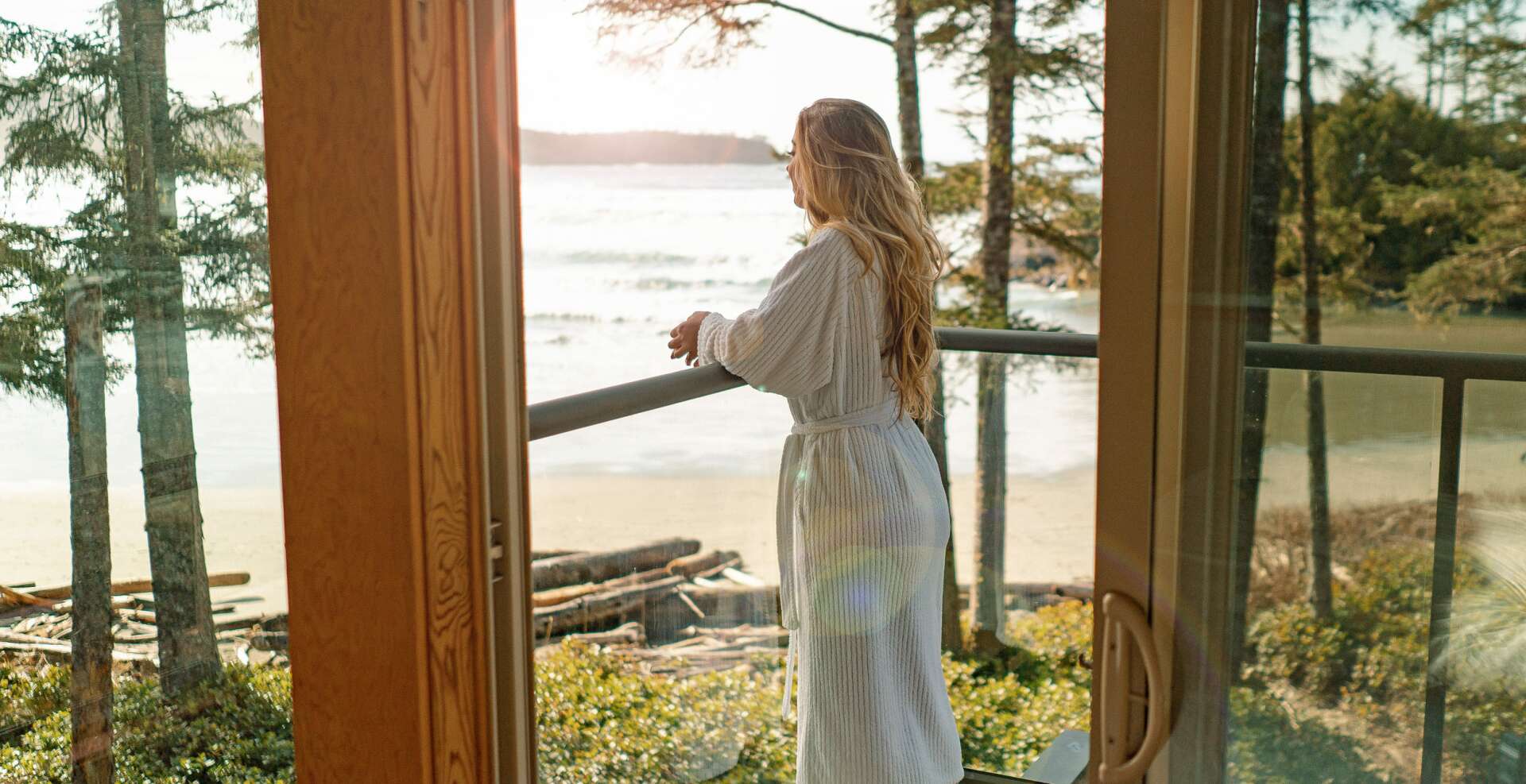 Girl in white bathrobe enjoying the morning views from her Beach House bedroom second floor deck.