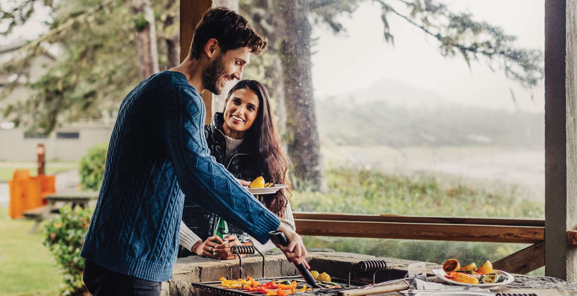 Diverse couple cooking dinner on the bbq outside the Beach Houses.