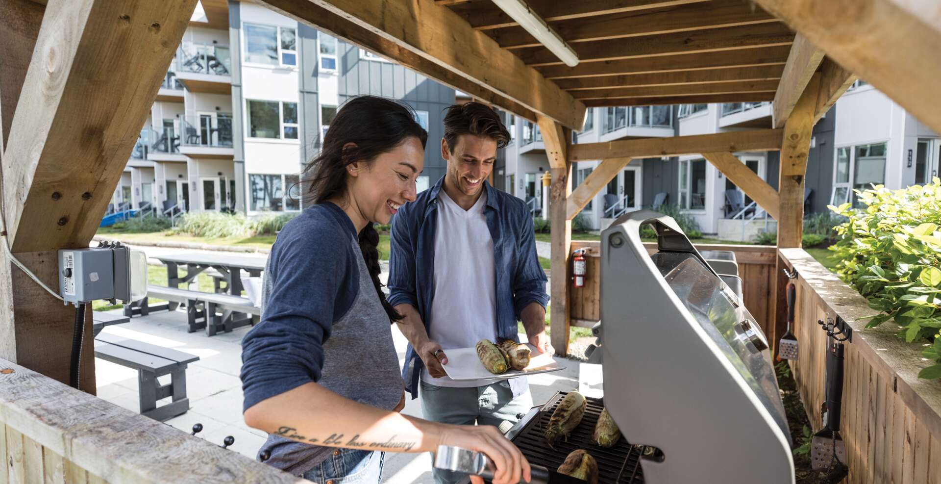 Couple cooking corn on gas bbq in front of Oceanside Suites.