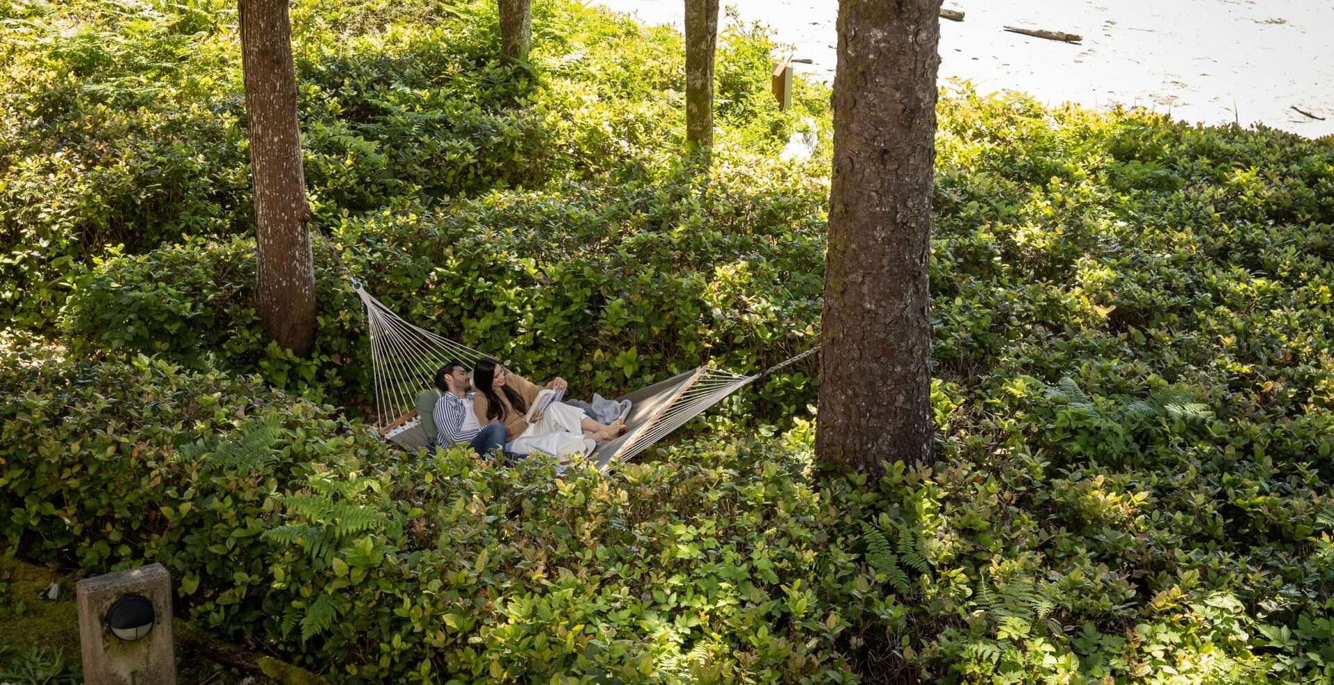 Couple relaxing on hammock in front of Beach Houses on Cox Bay.