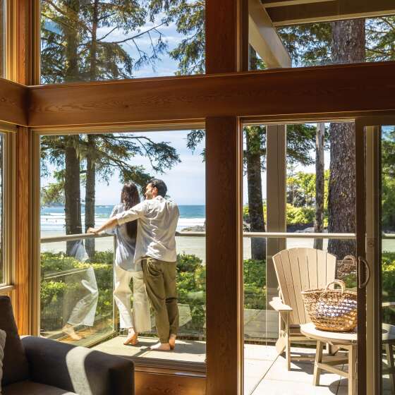 Couple taking in the sand and ocean views from their Beach House accommodation at Pacific Sands Beach resort.